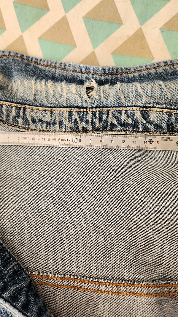 Col d’une veste en jean abîmé, troué et usé, avant réparation.