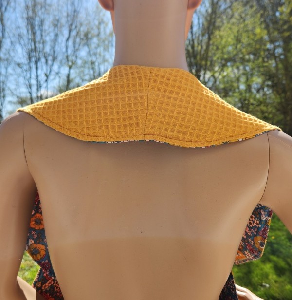 Vue arrière du châle de table élégant pour adulte, serviette croisée avec côté coton imperméable et côté nid d'abeille.