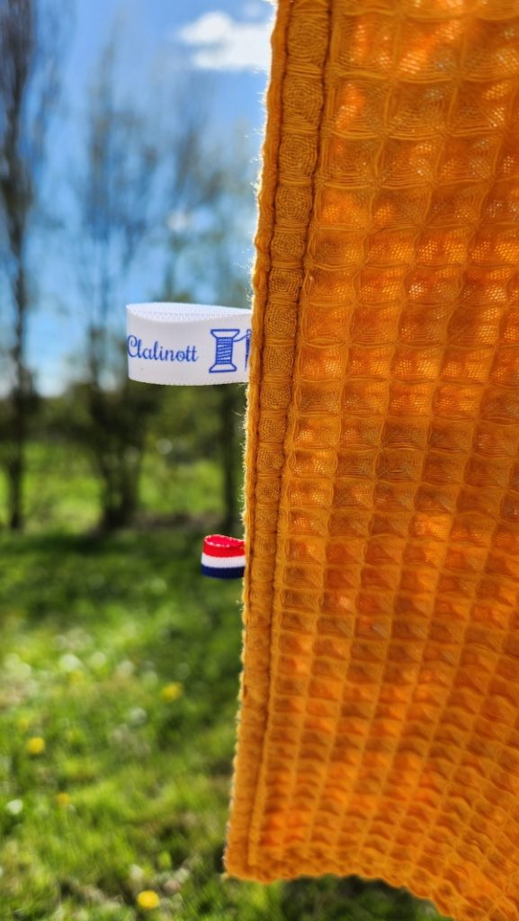 Vue du dos du châle de table élégant pour adulte, montrant les étiquettes et la finition avec le côté coton imperméable et nid d'abeille.