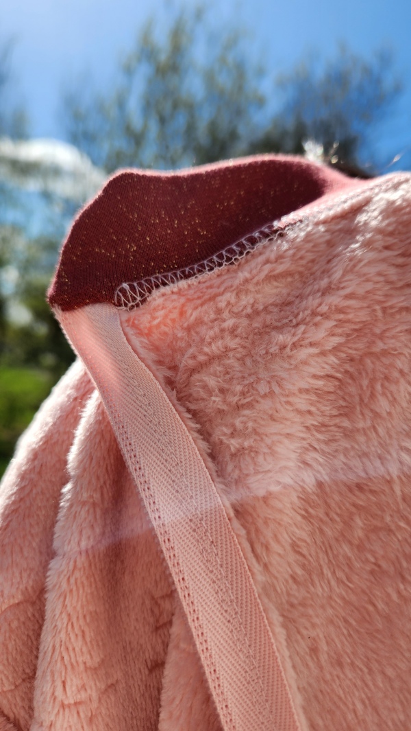 Grenouillère adaptée hiver chaude rose avec bord côte bordeaux pailleté, col intérieur avec finition soignée, conçue pour les personnes en situation de handicap.