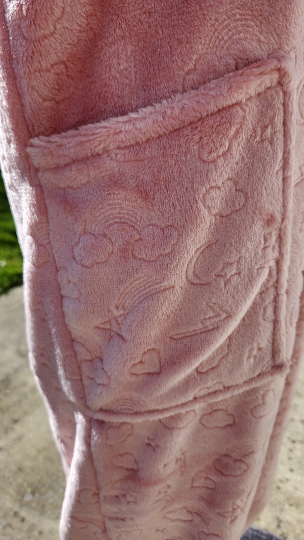 Poche avant sur une grenouillère adaptée rose avec bord côte vert pailleté.
