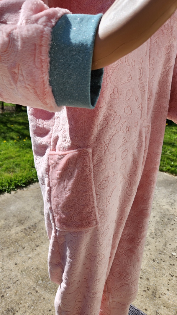 Poignet et poche avant sur grenouillère adaptée rose avec bords en côte vert pailleté, modèle chaud pour l’hiver.