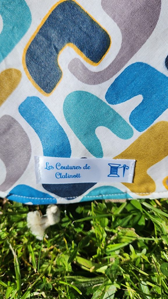 Tapis pieds au sec bleu, ocre, gris et blanc, côté imperméable avec étiquette Clalinott, accessoire piscine-plage.